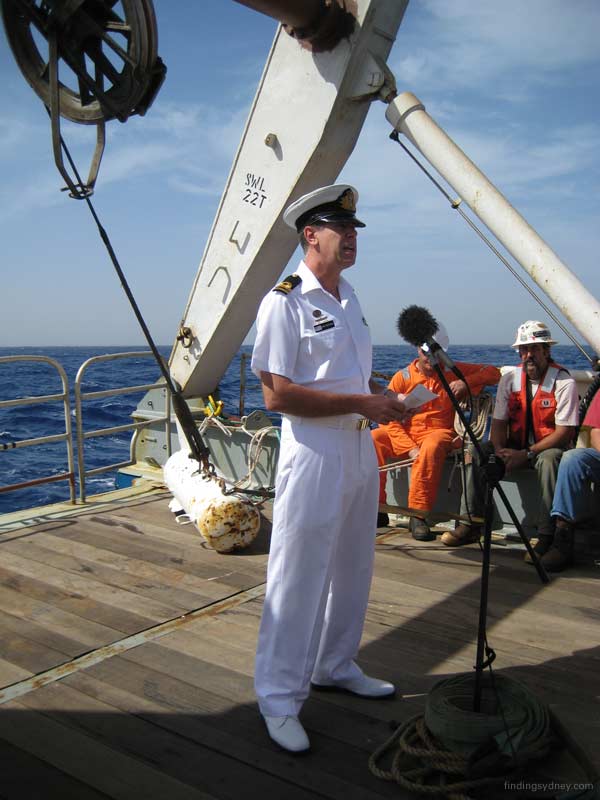 Lieutenant John Perryman reading from the order of service on the deck of the Geosounder.