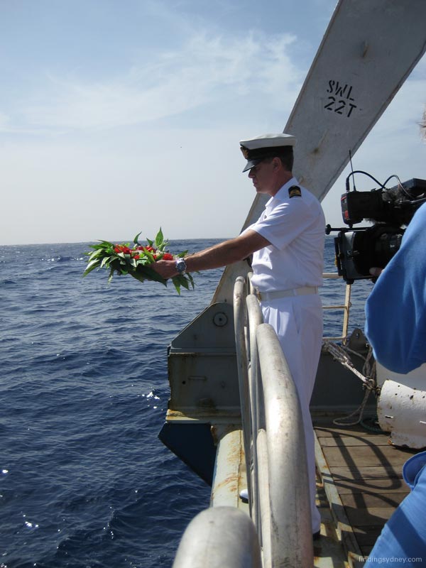 Lieutenant John Perryman preparing to cast a commemorative wreath into the ocean.