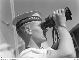 Keeping watch aboard HMAS Sydney, looking out to sea through binoculars is 23131 Signalman Frederick John Tebbutt.
