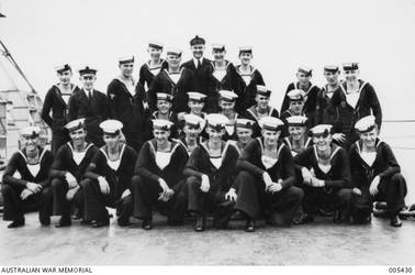 Group portrait of some of the Western Australian crew members of the RAN cruiser HMAS Sydney II on deck before going on leave. Standing at back, left to right: either 21073 Acting Leading Seaman Albert Frederick Harrington (*) or 22821 Stoker (Sto) Robert Alfred Miller (*); F2679 Sick Berth Attendant (SBA) Berny Nathan Shilkin; 23291 Sto Lyndon Irvine Roberts (*); 23161 Leading Stoker (Ldg Sto) Harry Clarke (*); 22281 Able Seaman (AB) Lawrence Thomas Byrne; F2231 James William Webster; F2437 AB Leonard John Howard (*); 23282 Sto Alfred Stockdale Clayton (*); F2611 AB Harold Ross Balding (*); R21198 Signalman (Sig) Clive Trood Stone; and 21266 Sto Leslie Michael Blom (*). Group of five, seated or crouching in centre, left to right: 23930 AB Kenneth George Taylor (*); 20604 Ldg Sto Thomas Charles Dixon (*); 21810 AB Arthur Eric Wayne; 23730 Sto Alfred Walter Clive (*) ; and 22077 AB Albert Edward Parkes. Front, crouching, left to right: 22279 AB Oswald Green; F2922 AB Clarence Frederick Buckingham (*); F2518 Sig Raymond William Carter; F2927 AB Malcolm Murray (*); 24044 Sto William Laurence Henderson (*); F2803 AB Thomas Patrick Fisher; 24049 AB Frederick Ernest Ward (*); 21585 AB Robert John Linklater; F2207 Leading Telegraphist Bertram Linsay Witton (*); F2806 AB Ross James Smith; and 24051 AB Harry Kenneth Short (*). Those crew members marked (*) were killed when HMAS Sydney was sunk in the Indian Ocean by the German auxiliary cruiser Kormoran on 20 November 1941. The other crew members in this portrait were no longer serving on HMAS Sydney at the time of its loss. Later in the war AB Parkes survived the sinking of HMAS Perth and internment as a prisoner of war (POW) of the Japanese.