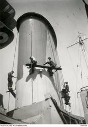 ALEXANDRIA, EGYPT. 1940-07. RAN PERSONNEL PAINTING THE SHIP'S NEW CAMOUFLAGE SCHEME ON THE AFTER FUNNEL OF THE CRUISER HMAS SYDNEY (II). THE DARK GREY IS PROBABLY 507A, BEING PAINTED OVER THE ORIGINAL LIGHT GREY 507C. (NAVAL HISTORICAL COLLECTION).