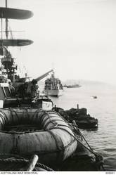 ADEN. 1940-05. A CARLEY FLOAT AND THE PORT 4 INCH GUN DECK OF THE CRUISER HMAS SYDNEY (II), LOOKING AFT. IN THE BACKGROUND IS THE CRUISER HMS GLOUCESTER AND AN OILER. (NAVAL HISTORICAL COLLECTION).
