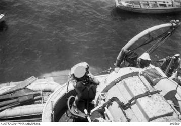 ALEXANDRIA, EGYPT. 1940-07-21. DETAIL VIEW OF THE PORT SEARCHLIGHT TAKEN FROM THE TOP OF THE FORWARD FUNNEL OF THE CRUISER HMAS SYDNEY (II). TORPEDOMEN ARE REPAIRING THE SEARCHLIGHT WHICH WAS DAMAGED DURING THE ACTION OFF CAPE SPADA WITH THE ITALIAN CRUISERS BARTOLOMEO COLLEONI AND GIOVANNI DELLE BANDE NERE. (NAVAL HISTORICAL COLLECTION).