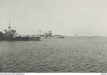 ALEXANDRIA, EGYPT. 1940-07-20. AFTER THE ACTION AGAINST THE ITALIAN VESSEL BARTOLOMEO COLLEONI OFF CAPE SPADA THE CRUISER HMAS SYDNEY (II) IS CHEERED INTO HARBOUR BY THE SHIPS OF THE MEDITERRANEAN FLEET WHICH CLEARED LOWER DECK TO WELCOME HER. SHE IS LEADING IN A BRITISH CRUISER, EITHER GLOUCESTER OR LIVERPOOL. THE WARSHIPS ON THE LEFT ARE THE BATTLESHIPS HMS WARSPITE (WITH AN OILER ALONGSIDE) AND MALAYA AND THE AIRCRAFT CARRIER HMS EAGLE. (NAVAL HISTORICAL COLLECTION).