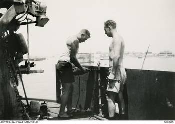 ALEXANDRIA, EGYPT. 1940-07. TWO SHIPWRIGHTS PUTTING UP 3/8 INCH STEEL PLATE AROUND 4 INCH GUN DECK TO PROTECT ANTI AIRCRAFT GUN CREWS ON THE CRUISER HMAS SYDNEY (II) FROM SHRAPNEL. (NAVAL HISTORICAL COLLECTION).