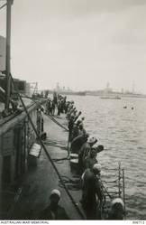 ALEXANDRIA, EGYPT. 1940-07-31. EGYPTIAN WORKERS ON BOARD THE CRUISER HMAS SYDNEY (II) INSTALLING DEGAUSSING EQUIPMENT AS A PROTECTION AGAINST MAGNETIC MINES. IN THE BACKGROUND ARE THE INTERNED FRENCH CRUISERS SUFFREN AND TOURVILLE. (NAVAL HISTORICAL COLLECTION).