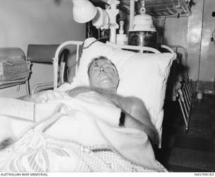 An injured sailor, possibly R23349 Naval Shipwright 1 Thomas 'Jesse' James, rests in a sick bay bunk of the RAN aircraft carrier HMAS Melbourne (II). He was rescued following the sinking of HMAS Voyager on the night of 10 February 1964, the result of a collision with HMAS Melbourne during exercises off Jervis Bay, southern NSW. The disaster claimed the lives of 82 crew members of the Voyager. Naval Shipwright James served in the RAN during the Second World War, enlisting on 10 July 1939. After the collision between HMAS Melbourne and HMAS voyager, Naval Shipwright James stayed in the RAN and served a tour of duty in the Vietnam War on HMAS Sydney, from March 1967 to November 1968. He retired from the navy in 1971.