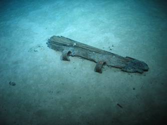 Wooden post with metal hinges. Possibly rudder post from boat